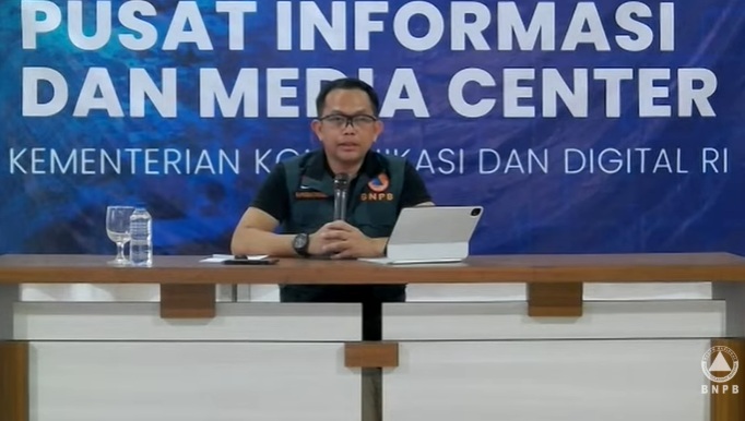 Kepala Pusdatinkom BNPB Abdul Muhari menggelar konferensi pers di Pusat Informasi dan Media Center Komdigi di lobi Kantor Gubernur Aceh, Kota Banda Aceh, Minggu (14/12/2025). (Tangkapan layar saluran resmi BNPB di YouTube)